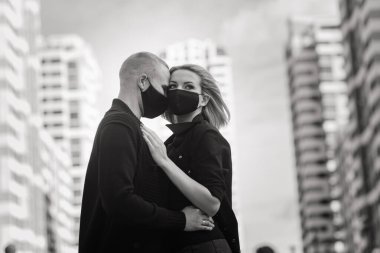 Karantina sırasında şehrin boş sokaklarında yürüyen şık koruyucu maskeler takan bir çift..