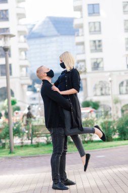 Karantina sırasında şehrin boş sokaklarında yürüyen şık koruyucu maskeler takan bir çift..