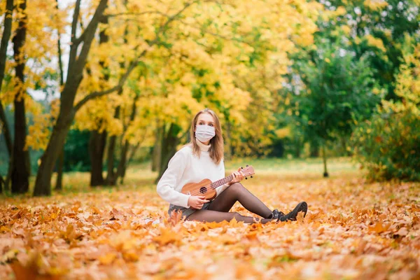 Retrato Mujer Joven Máscara Protectora Tocando Guitarra Ukelele Parque Otoño —  Fotos de Stock