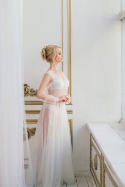 Yatak odası elbisesi içinde güzel bir gelinin sabahı. Stüdyo, iç mekan.