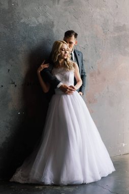 Klasik bir stüdyonun içinde şirin bir düğün çifti. Öpüşüyorlar ve sarılıyorlar..