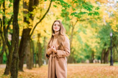 Güzel bir kadın sonbahar mevsiminde parkta vakit geçiriyor.