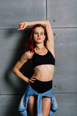 Stüdyoda beton arka planda fitness yapan kadının portresi.