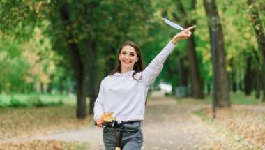 Şehir parkında covid salgını sırasında koruyucu yüz maskesi takan sıradan bir beyaz kadın. Kentsel hareketlilik kavramı.