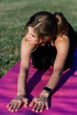 Genç bir bayan stadyumda yoga yapıyor.