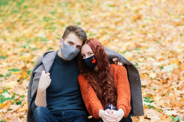 在秋天的公园里 红头发的年轻女子和年轻男子一起散步时 戴着面具 — 图库照片