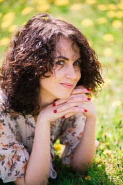 Bahar çiçekli bahçede poz veren kıvırcık saçlı çekici bir kadın.