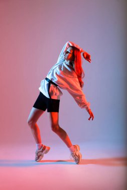 Stüdyoda hip-hop yapan genç bir bayan, sıradan kıyafetler.