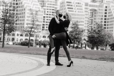 Karantina sırasında şehrin boş sokaklarında yürüyen şık koruyucu maskeler takan bir çift..