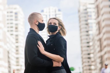 Karantina sırasında şehrin boş sokaklarında yürüyen şık koruyucu maskeler takan bir çift..