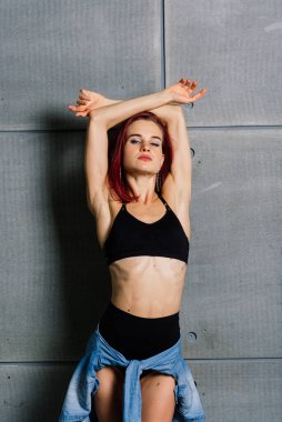 Stüdyoda beton arka planda fitness yapan kadının portresi.