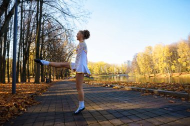 Sonbahar yaprakları arasında doğa parkında dans eden balerin..
