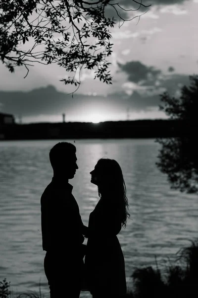 Couple in love back light silhouette at lake orange sunset, romantic.