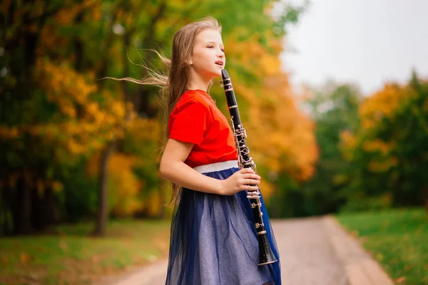 Νεαρή Ελκυστική Κοπέλα Παίζει Κλαρινέτο Στο Πάρκο Φθινόπωρο — Φωτογραφία Αρχείου