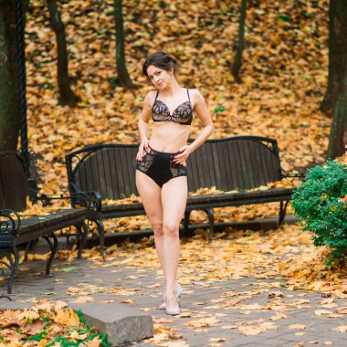 Güz ormanında iç çamaşırlı güzel bir kadın poz veriyor.