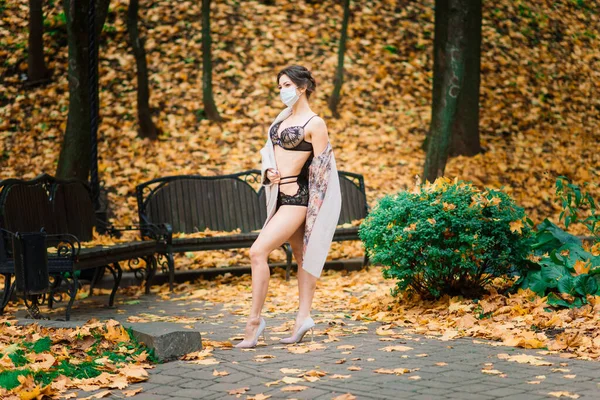 秋の公園で顔のマスクやランジェリーでセクシーな女性のファッションの肖像画 パンデミック ウイルス コロナウイルス — ストック写真