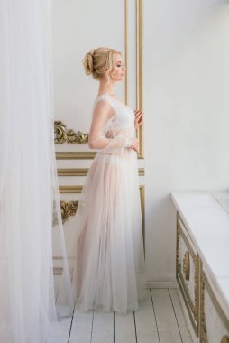 Yatak odası elbisesi içinde güzel bir gelinin sabahı. Stüdyo, iç mekan.