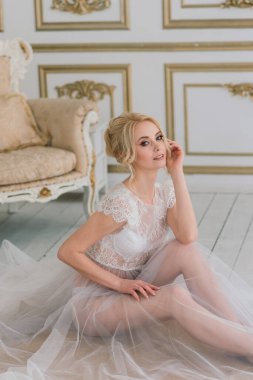 Yatak odası elbisesi içinde güzel bir gelinin sabahı. Stüdyo, iç mekan.