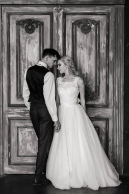 Klasik bir stüdyonun içinde şirin bir düğün çifti. Öpüşüyorlar ve sarılıyorlar..