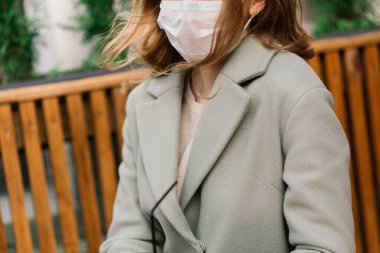 Kafkasyalı bir kadının tıbbi maske taktığı ve arka planda bir kafenin önünde duran portresini yakından çek.