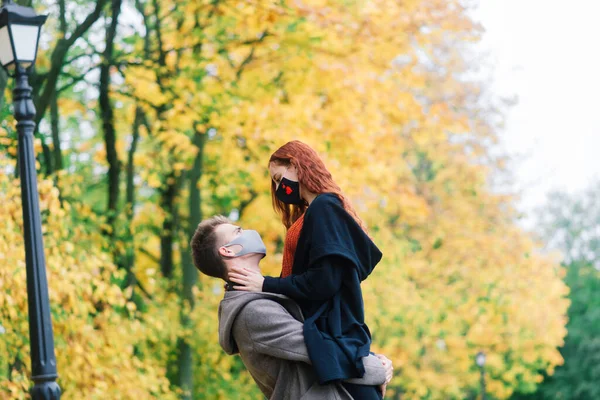 Young couple wearing masks together in forest, park