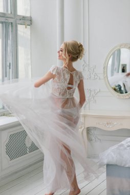 Kavramsal düğün, gelinin Avrupa tarzında bir sabah. Yatak odası elbisesi, iç stüdyodaki ücretler. Gelin için beyaz minimalizmi