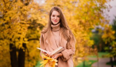 Güzel bir kadın sonbahar mevsiminde parkta vakit geçiriyor.