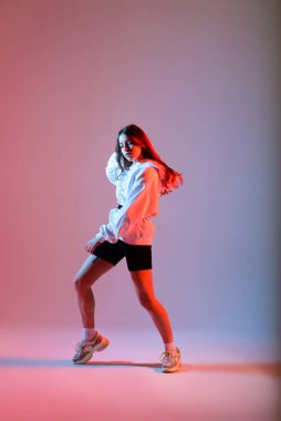 Stüdyoda hip-hop yapan genç bir bayan, sıradan kıyafetler.