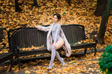 Güz parkında iç çamaşırlarıyla poz veren ince vücutlu, güzel, koyu renk saçlı bir kadın.