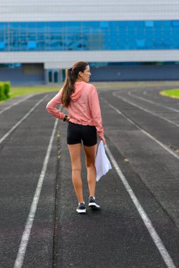 Sporcu atletizm pistinde koşuyor ve kardiyo çalışıyor. Kadınlar yaz stadyumunda yarışmak için koşuyorlar..