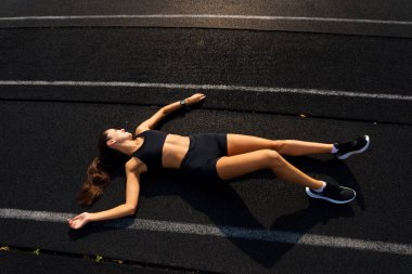 Sporcu atletizm pistinde koşuyor ve kardiyo çalışıyor. Kadınlar yaz stadyumunda yarışmak için koşuyorlar..