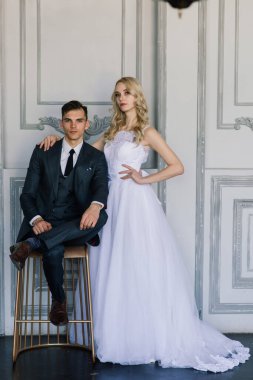 Klasik bir stüdyonun içinde şirin bir düğün çifti. Öpüşüyorlar ve sarılıyorlar..