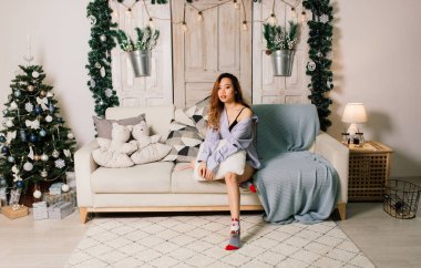 Güzel, genç Asyalı bir kadın Noel 'i evde kutluyor, hediyeleri açarken eğleniyor.