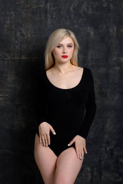 Siyah tulumlu, parlak makyajlı genç, tombul kadın arka planda poz veriyor, fotokopi alanı ile izole edilmiş. XXXL moda ve abur cubur kavramı