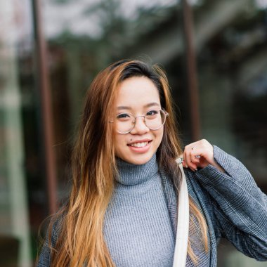 Güzel genç Çinli öğrenci sokakta kitap tutuyor.