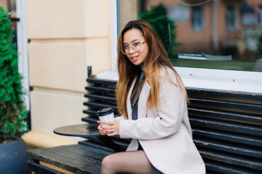 Güzel genç Çinli öğrenci sokakta kitap tutuyor.