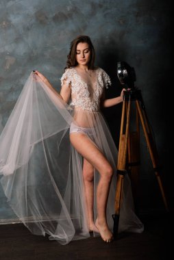 Beyaz iç çamaşırlı güzel gelin yatak odasında ve stüdyosunda oturuyor. Düğün konseptinin sabahı