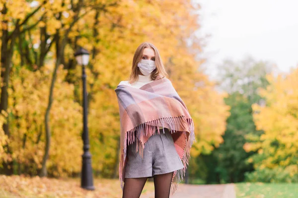 一个年轻的女人在公园里散步时保护自己不感染日冕病毒 秋季背景 — 图库照片