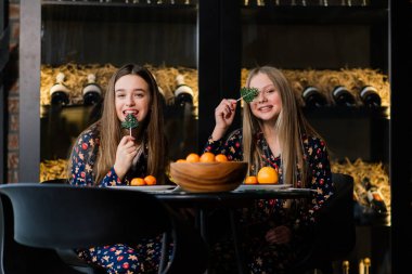 Yeni yıl arifesini ve Noel 'i kutlayan ve yatakta mandalina yiyen kızlar. Hediyeler ve altın toplarla süslenmiş köknar dalları var..