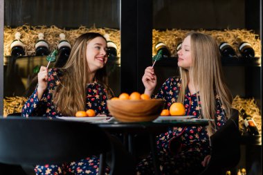 Yeni yıl arifesini ve Noel 'i kutlayan ve yatakta mandalina yiyen kızlar. Hediyeler ve altın toplarla süslenmiş köknar dalları var..