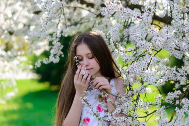 Güzel bir bahar gününde, çiçek açan elma bahçesinde güzel bir kız.