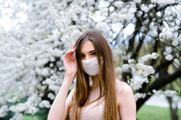 在春天的花园里 脸上戴着无菌防护口罩的年轻女子 — 图库照片