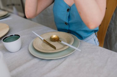 Neşeli, duygusal genç bir kadın, evdeki mutfakta tabakları olan ahşap bir masada oturuyor.