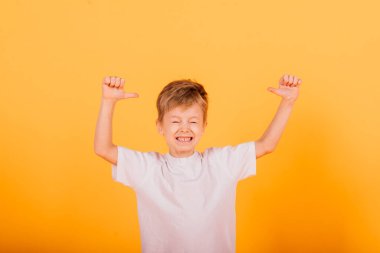 Portrait of happy little boy over yellow background in studio clipart