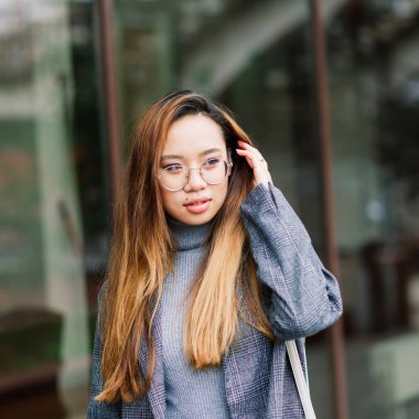 Güzel genç Çinli öğrenci sokakta bir fincan kahve tutuyor.