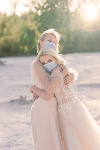 Lesbian couple wedding, wear masks to prevent epidemic covid, on sand background