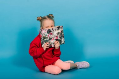 Küçük anaokulu çocuğu mavi üzerine izole bir şekilde kitap okurken öğreniyor.