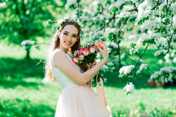 白いウェディングドレスの花嫁は緑の公園で花束を持っています 晴れた日の夏の結婚式 — ストック写真