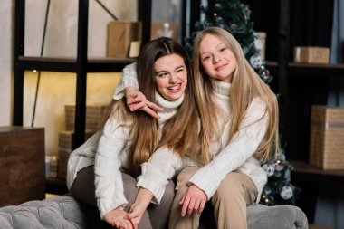 Yeni yıl arifesini ve Noel 'i kutlayan ve yatakta mandalina yiyen kızlar. Hediyeler ve altın toplarla süslenmiş köknar dalları var..