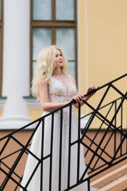 Parkta yürüyen ve gülümseyen kıvırcık saçlı sarışın gelin, konsept düğün.